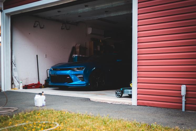 A blue car inside of a red garage.