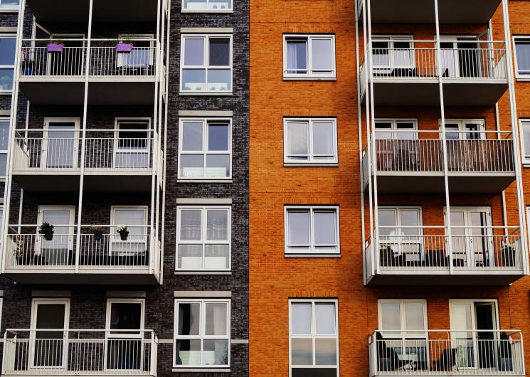 A block of flats with balconies, one side is black and the other is orange.