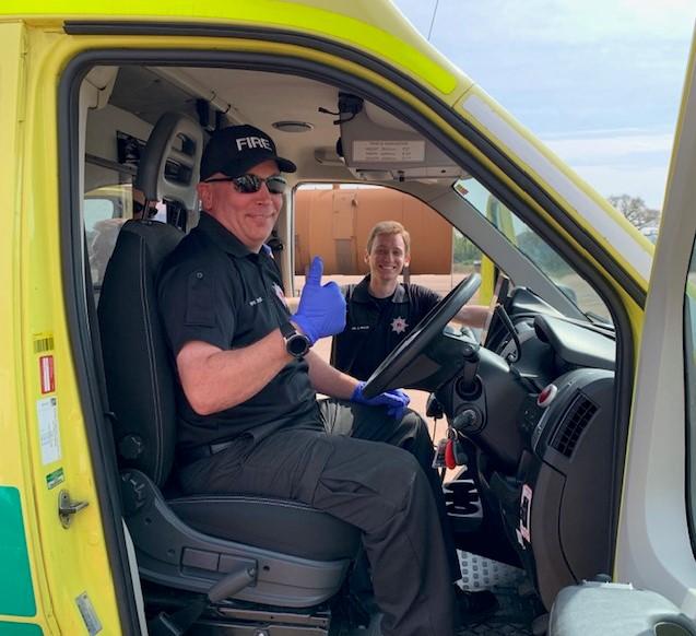 A firefighter sitting at the driving wheel of an ambulance